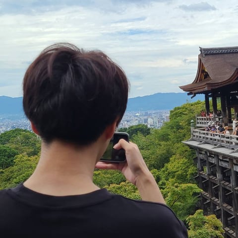 Moto, seen from behind, taking a photo of Kiyomizu-dera in Kyoto